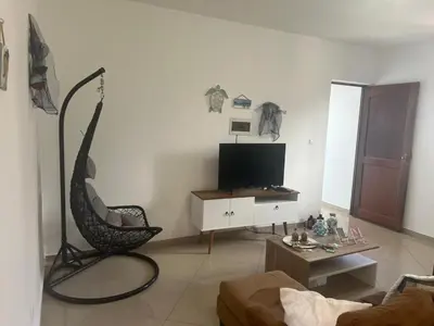 a living room with a chair and a flat screen tv at Techas Stylish 2-Bedroom 8 min to Beach in Tarrafal
