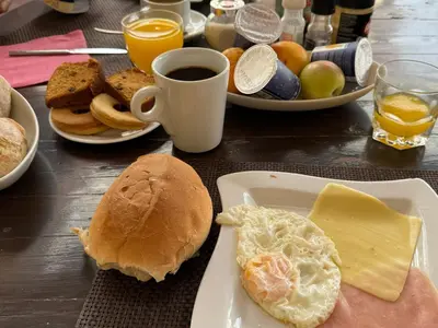 a table with plates of breakfast foods and a cup of coffee at Pensao Porta do Vento in Santa Maria