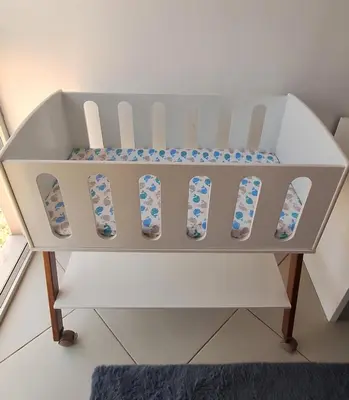 a white crib with blue and white accents at Sinta-se em casa! in Praia