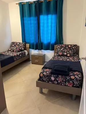 two beds in a room with blue curtains at Bayview Bliss Appartement in Santa Maria