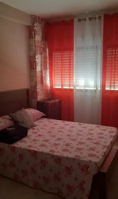 a bedroom with a bed with red walls and windows at Apartamento Mi in Praia
