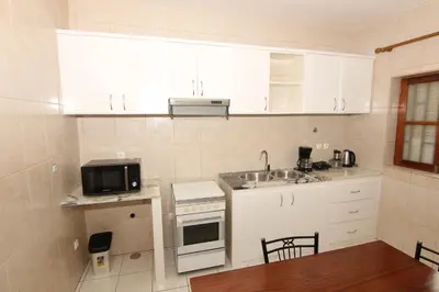 a kitchen with white cabinets and a sink and a microwave at Kasa Tabuga in Porto Novo