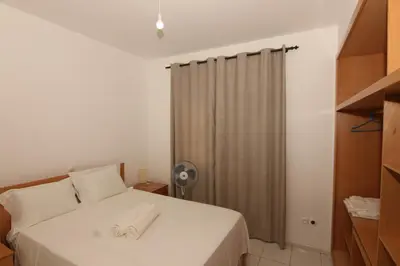 a bedroom with a white bed and a fan at Kasa Tabuga in Porto Novo