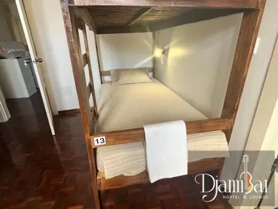 a small bed in a wooden frame in a room at Hostel Djambai in Mindelo