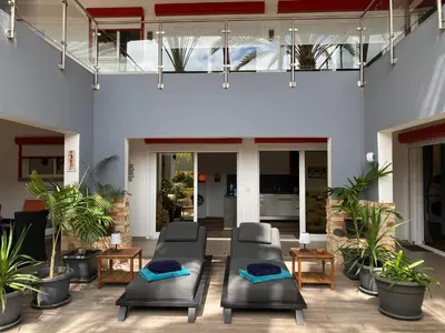 a patio with chairs and tables and potted plants at Zweite Heimat - Townhouse Boa Vista in Sal Rei