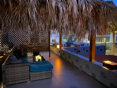 a rooftop bar with a large straw umbrella and a table at Zweite Heimat - Townhouse Boa Vista in Sal Rei