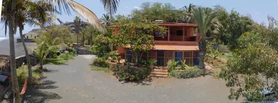 a house on the side of a beach with palm trees at Tortuga B&B in São Filipe