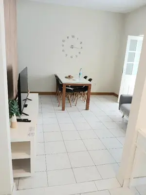 a living room with a table and a clock on the wall at Flat Mindelo Deluxe 30 in Mindelo