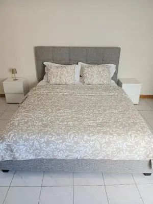 a large bed with a gray headboard and pillows at Flat Mindelo Deluxe 30 in Mindelo