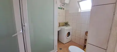 a bathroom with a toilet and a washing machine at Mendes Family Guesthouse, and Services in Praia