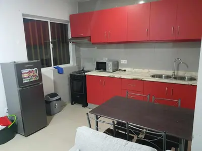 a kitchen with red cabinets and a table and a refrigerator at Elizabeth Rocha in Mindelo