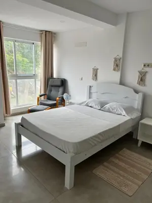 a bedroom with a large bed and a chair at Apartamentos Baia Marginal 1 in Mindelo