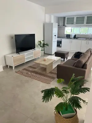a living room with a tv and a couch and a table at Apartamentos Baia Marginal 1 in Mindelo