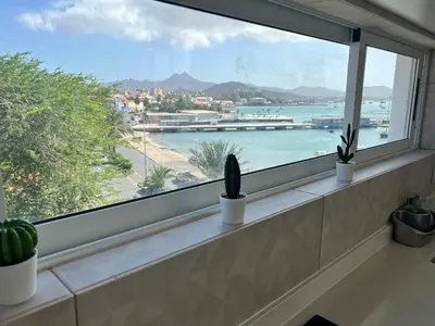 a window with potted plants and a view of a harbor at Apartamentos Baia Marginal 1 in Mindelo