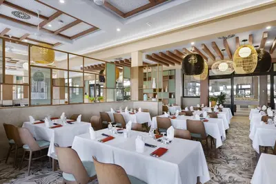 a restaurant with white tables and chairs and windows at Hotel Riu Palace Santa Maria - All Inclusive in Santa Maria