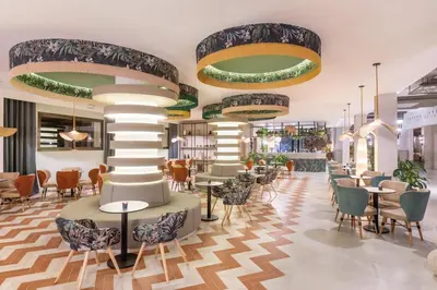 a lobby with tables and chairs and a column at Hotel Riu Karamboa - Adults Only - All Inclusive in Rabil