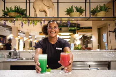 a woman sitting at a counter with two drinks at Hotel Riu Karamboa - Adults Only - All Inclusive in Rabil