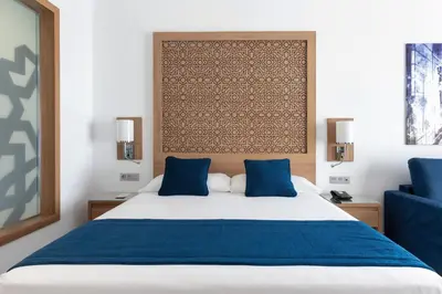 a bedroom with a large bed with blue pillows at Hotel Riu Palace Boavista - All Inclusive in Boa Ventura