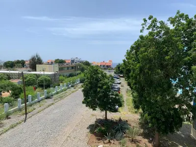 a road with trees and cars parked in a parking lot at Kaza Awa - Urban Guesthouse in Praia