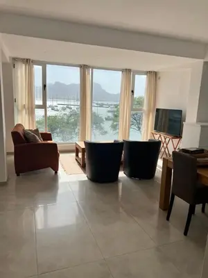 a living room with couches and a tv and windows at Apartamento Baia Marginal 2 in Mindelo