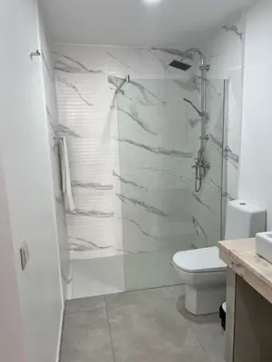 a white bathroom with a shower and a toilet at Apartamento Baia Marginal 2 in Mindelo