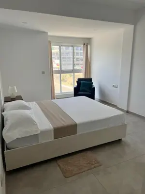 a bedroom with a bed and a chair and a window at Apartamento Baia Marginal 2 in Mindelo
