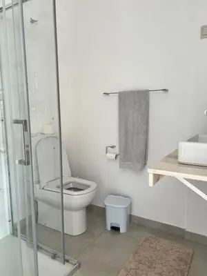 a bathroom with a toilet and a glass shower at Apartamento Baia Marginal 2 in Mindelo