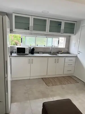 a kitchen with white cabinets and a microwave at Apartamento Baia Marginal 2 in Mindelo