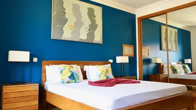 a bedroom with a bed with blue walls and a mirror at Spacious Penthouse with BBQ and Views in Praia