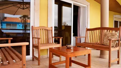 a porch with two wooden chairs and a table at Spacious Penthouse with BBQ and Views in Praia