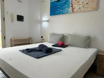 a white bed with two towels on top of it at Raio Do Sol - Beach front studio with city view in Santa Maria