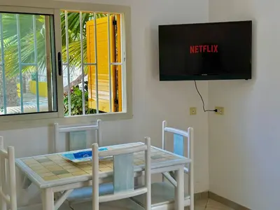 a table and chairs with a tv on a wall at Raio Do Sol - Beach front studio with city view in Santa Maria