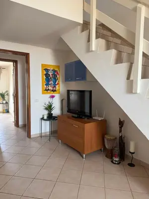 a living room with a tv and a staircase at Leme Bedje - Two bedroom, Pool, WiFi & Beachfront in Santa Maria
