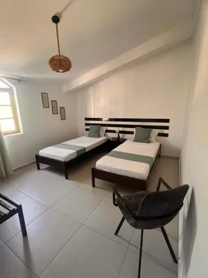 a room with two beds and a chair in it at Bed and breakfast Residencial Maravilha in Mindelo