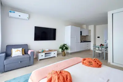 a bedroom with a bed and a couch and a kitchen at Apartamentos Golfinho Dourado `Edifício Lux,s in Santa Maria