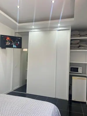 a bedroom with a white sliding door and a bed at Apto Duarte quarto no terraço in Praia