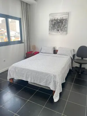 a bedroom with a bed and a chair at Apto Duarte quarto no terraço in Praia