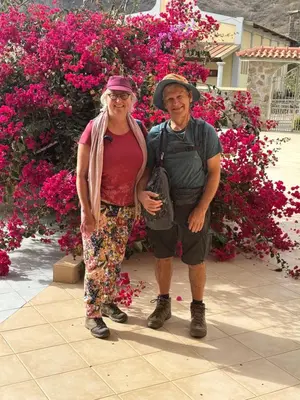a man and a woman standing in front of pink flowers at Conforto ,Natureza e Relaxamento in Carvoeiros