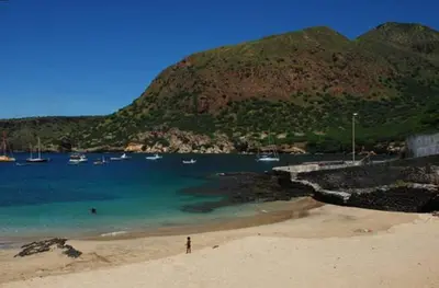 a person standing on a beach with boats in the water at Self-catering Apartment w/ Terrace in Tarrafal