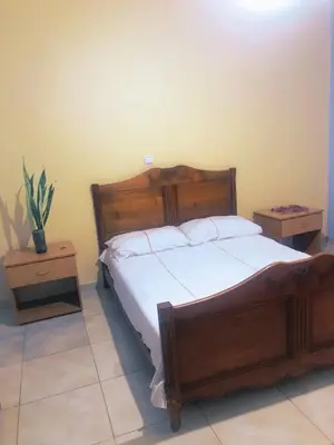a bedroom with a large wooden bed and two night stands at Conforto no Coração do Tarrafal in Tarrafal