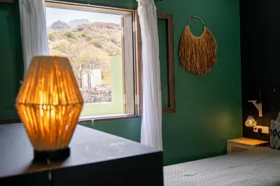 a bedroom with a window and a table with a lamp at Casa Archipel - Lagedos in Ribeira Fria