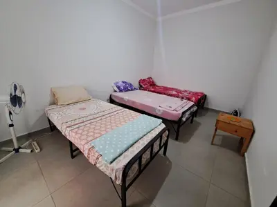 three beds in a room with a fan at Barros Homestay in Tarrafal