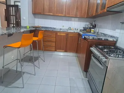 a kitchen with wooden cabinets and orange chairs in it at Barros Homestay in Tarrafal