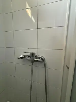 a shower with a hose in a white tiled bathroom at Casa Cisalta N2 - 5mn Centro City in Praia