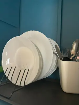 a stack of white plates and a container of utensils at Casa Cisalta N5 - Quarto Casal in Praia