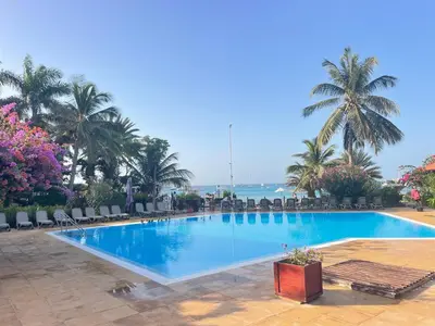 a large swimming pool with palm trees and the ocean at Porto Antigo 2 studio 15 beach and pool in Santa Maria