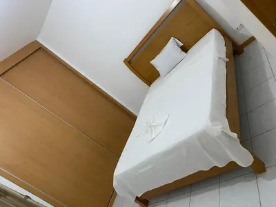 a bed with white sheets and pillows in a room at Apartment 3 minutes from Nelson Mandela Airport in Praia