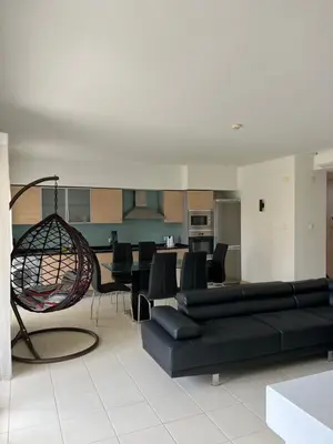 a living room with a black couch and a kitchen at Soares Appart's in Santa Maria