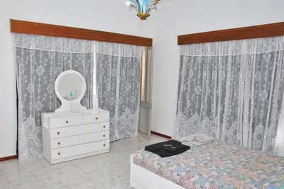 a bedroom with a bed and a dresser and a mirror at Tambarina Guest House in Mindelo