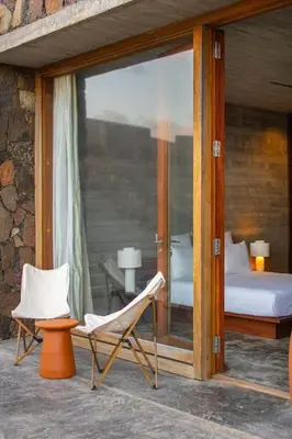 a patio with a chair and a bed and a window at Villa, Vue Mer et Piscine Privée in Mindelo